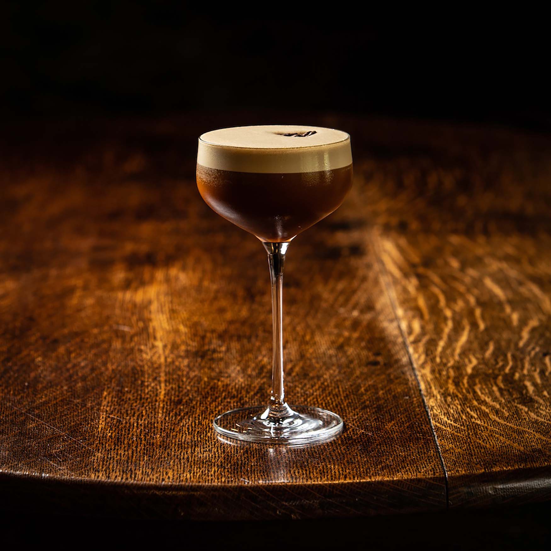 Image of an espresso martini sitting on a wooden table
