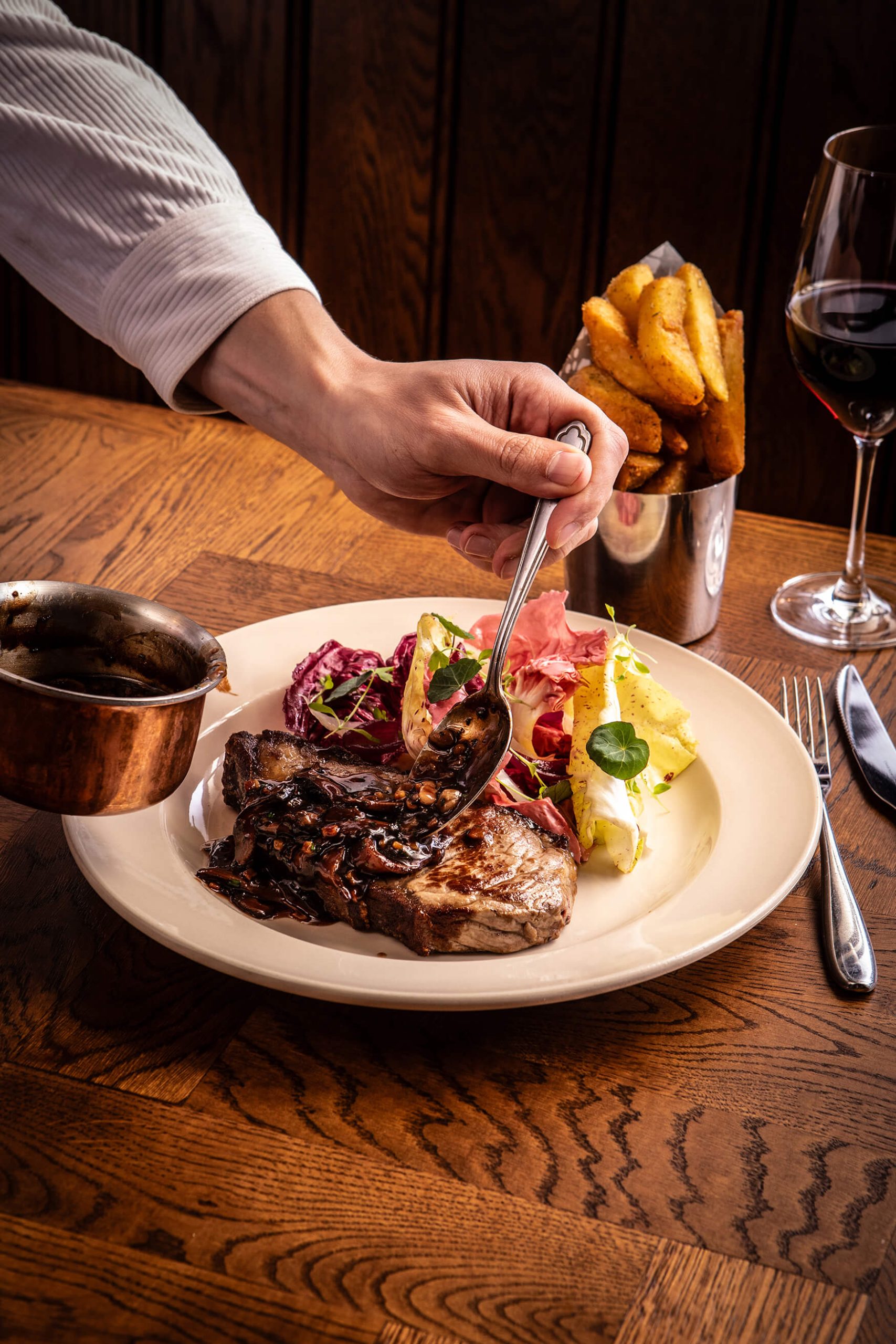Image showing someone pouring jus over a perfectly cooked stake with salad and chips at The General Tarleton