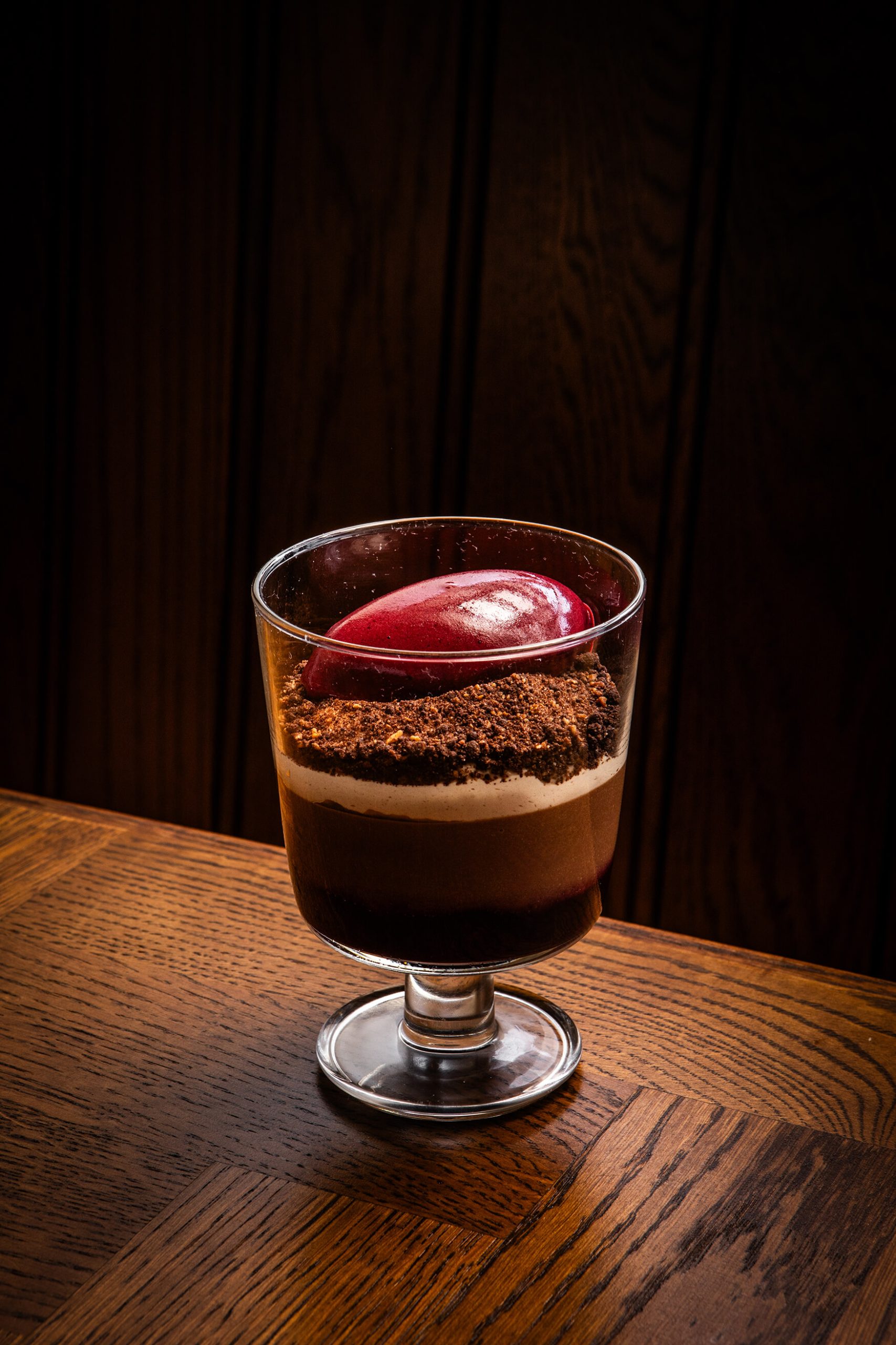 Image of a chocolate mouse with raspberry in a wine glass sitting on a wooden table at The General Tarleton