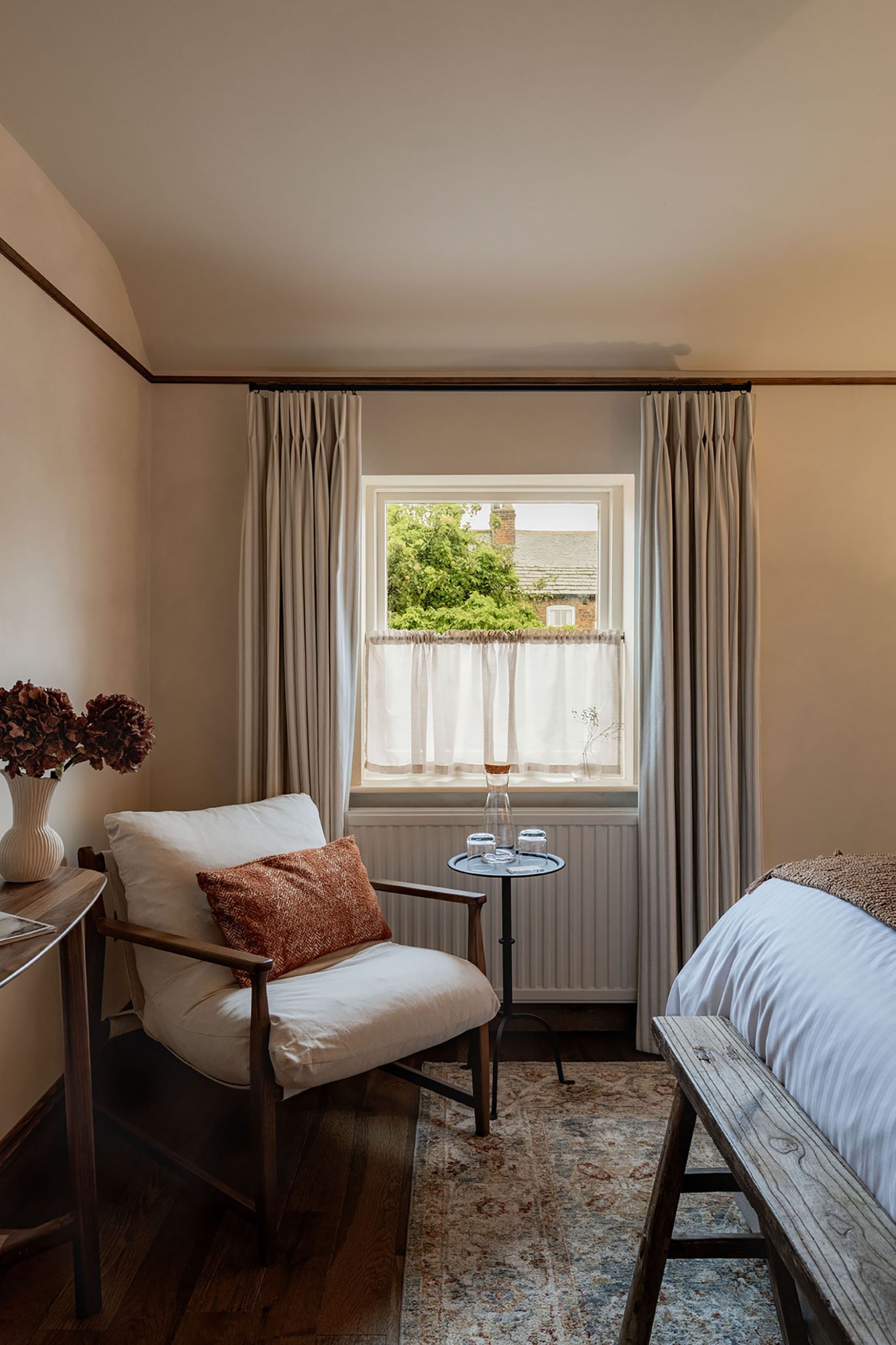 Image of a bedroom at The General Tarleton showing a comfortable cream armchair with red cushion by a window