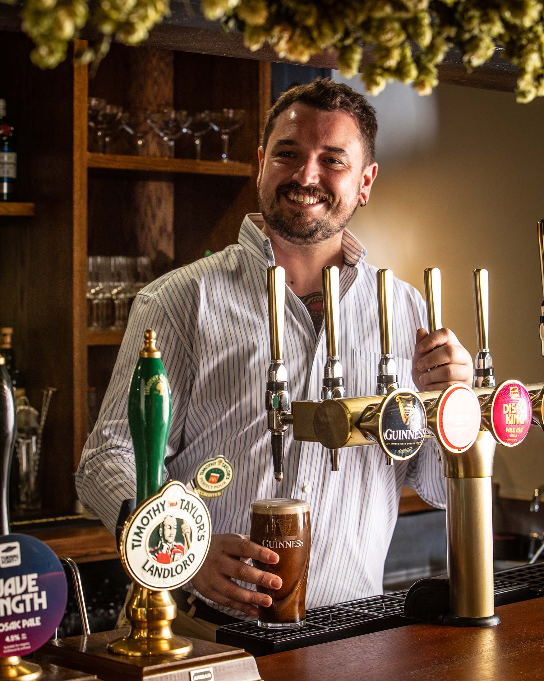 Image showing a man in a striped shirt pulling a pint behind the bar in a pub, The General Tarleton