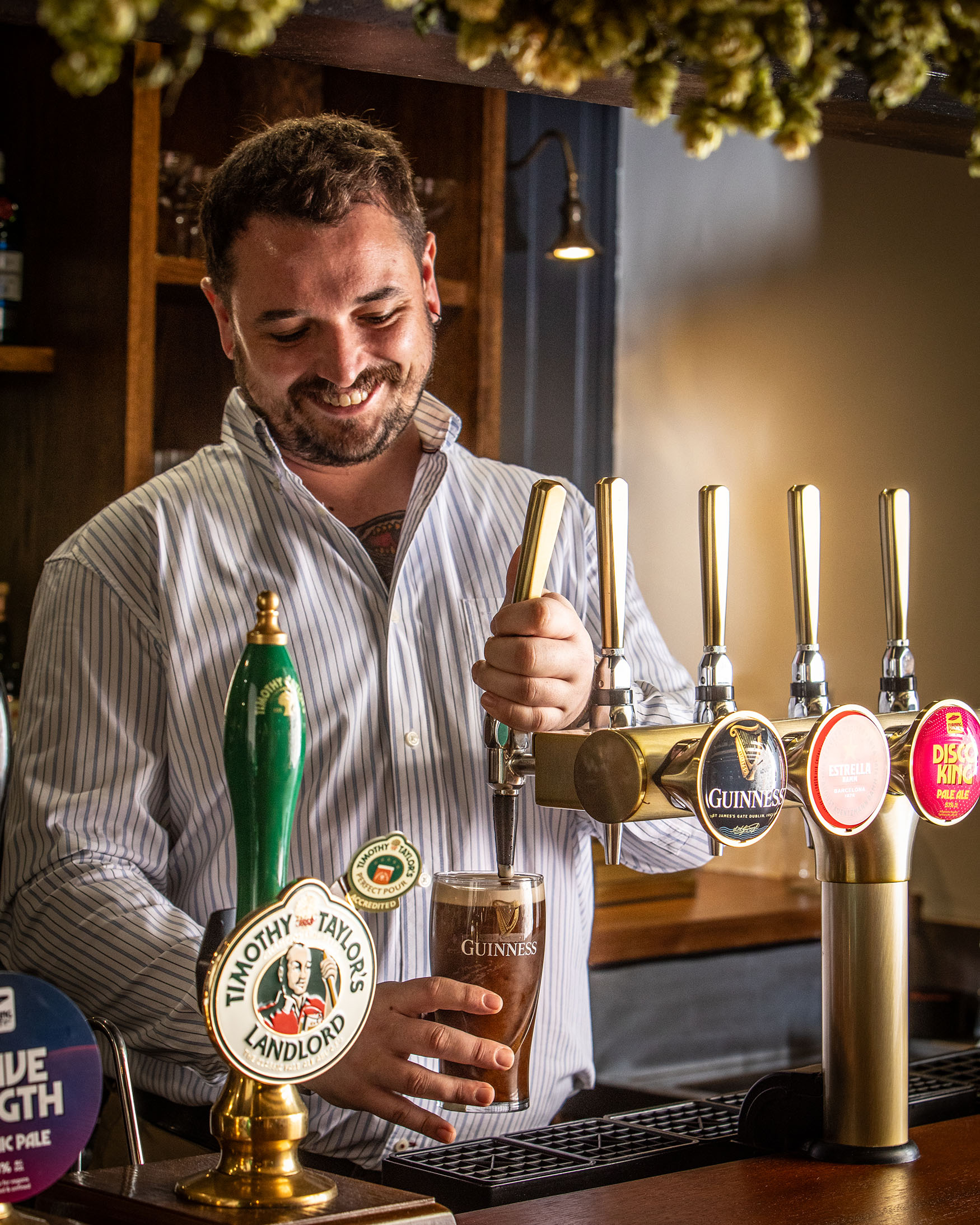 Image showing a man in a striped shirt pulling a pint behind the bar in a pub, The General Tarleton